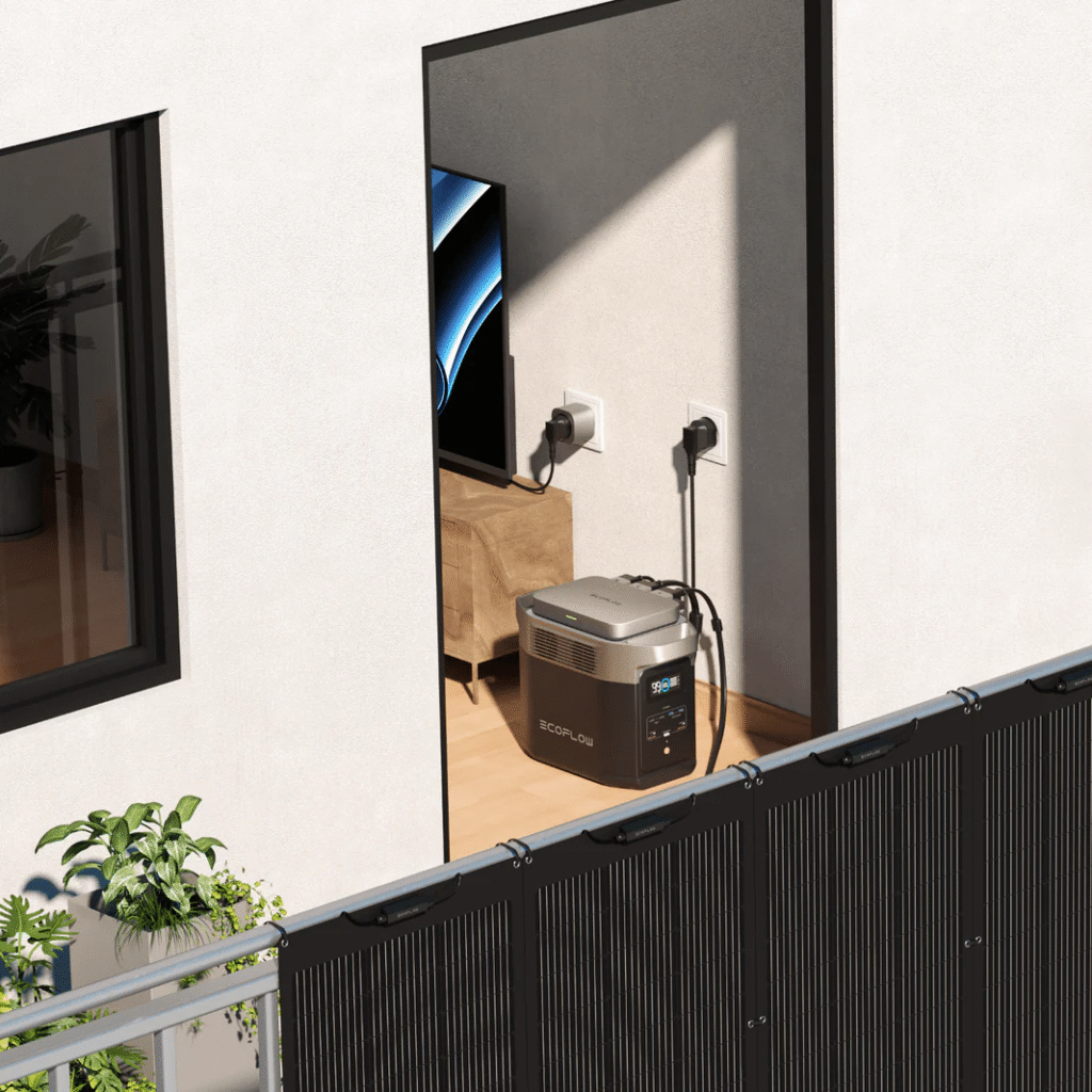 EcoFlow draagbaar krachtstation in grijs, aangesloten op binnenhuis stopcontact, met zwart EcoFlow zonnepaneel op balkon leuning, geschikt voor off-grid energievoorziening thuis.