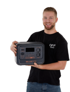 Bluetti Premium 100 draagbaar powerstation in antraciet met LED display en meerdere aansluitingen, vastgehouden door man met zwart Off Grid T-shirt.