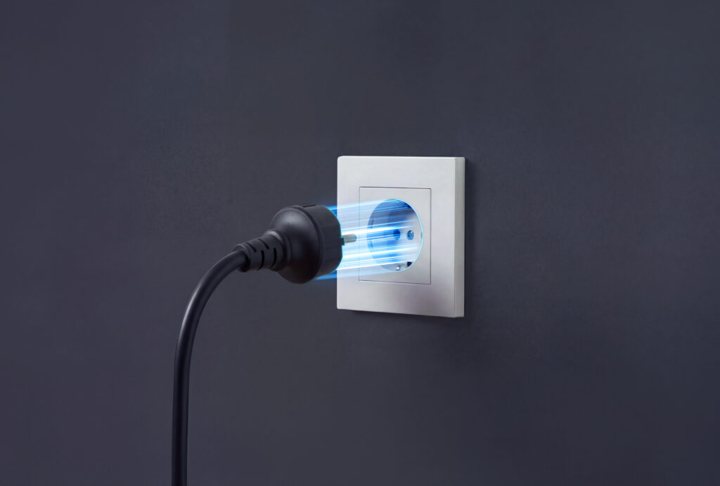 Een plug en play thuisbatterij, zwarte stekker met blauwe stroomlijnen die in een wit stopcontact in een donkere muur wordt gestoken, symboliserend energie en elektriciteit.